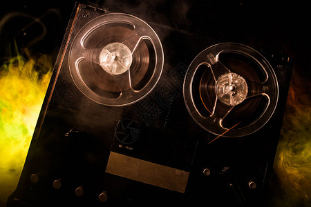 开盘在即旧的老式卷轴到卷轴播放器和录音机在深色调的雾背景上带卷盘的模拟立体声开盘式录音机播放器背景