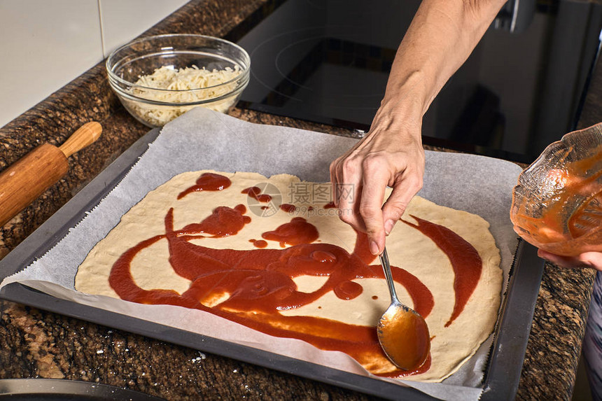 女人手在面团上做美味的比萨饼图片