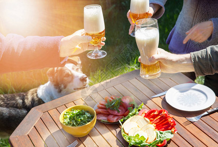 人们和狗在夏日的阳光下在家里花园里吃晚饭图片