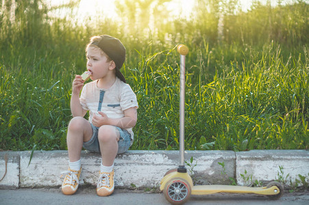 快乐的孩子吃和骑摩托车花园里拿着冰淇淋的男孩快乐的男孩图片