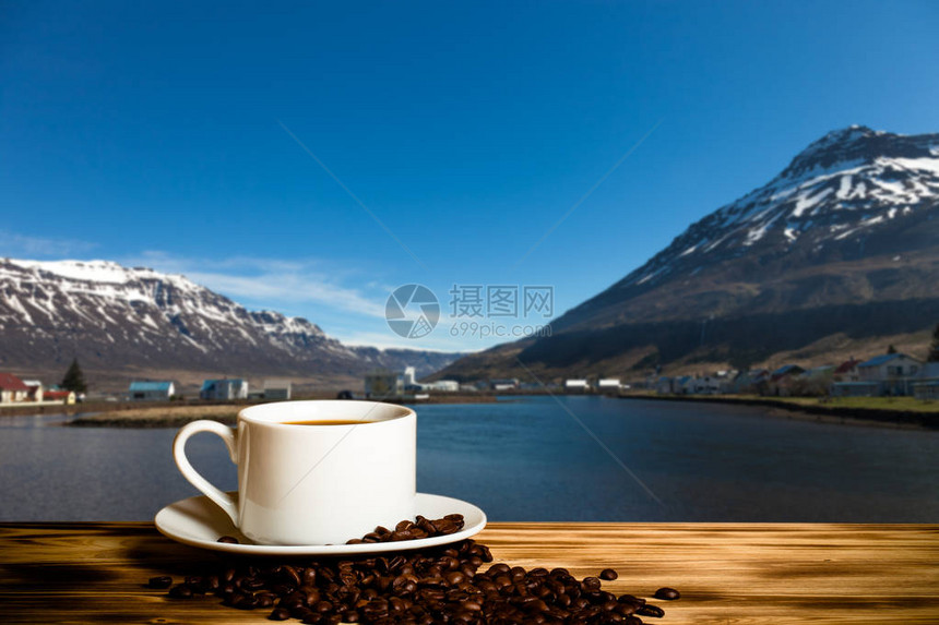 咖啡和白杯放在木制桌子上在冰岛峡湾的雾色风景图片