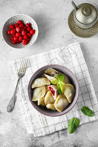 薄荷樱桃饺子灰色背景的碗里有浆果的自制甜饺子美味的樱桃饺子美食摄影图片
