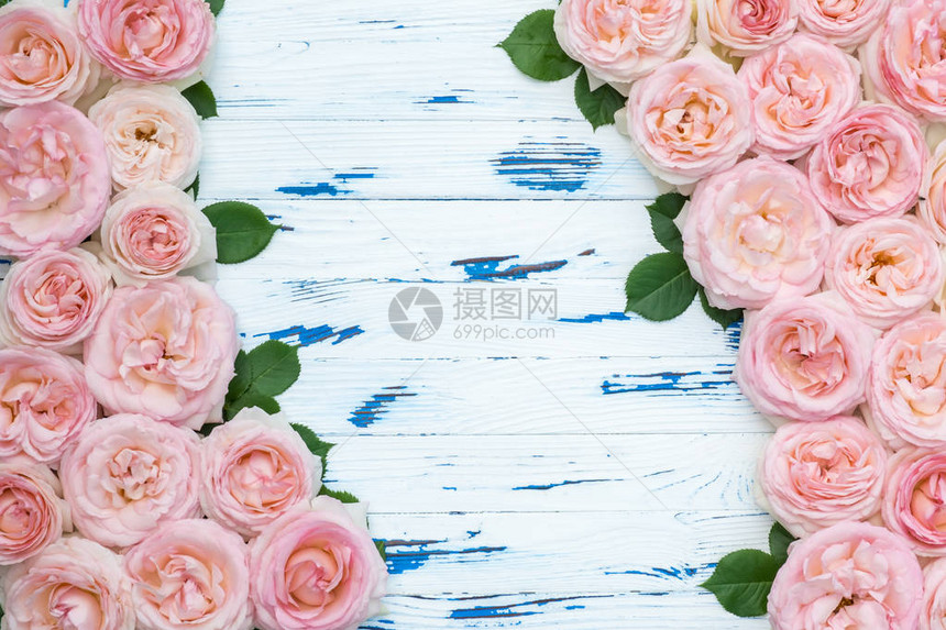 框架由粉红色的玫瑰与老年蓝色木制背景上的叶子制成图片