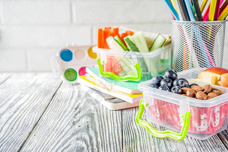 健康的学校午餐盒带三明治水果蔬菜坚果水和学习用品的儿童午餐盒图片