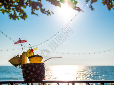 菠萝果汁鸡尾酒在沙滩附近在蓝色的天空和海景图片