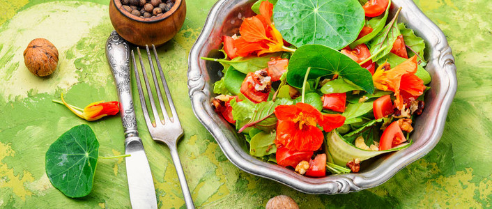 用鲜花金莲花叶西红柿和坚果制成的健康沙拉印度沙拉食品背景图片