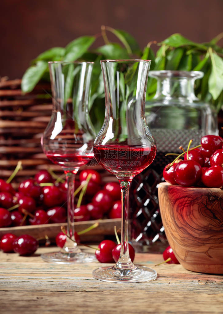 樱桃酒和红樱桃放在花园的木桌上的木碗里图片