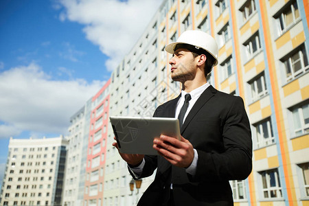 高帅的中东商人戴硬帽站在建筑工地复制空间的公寓楼对面站立不动图片