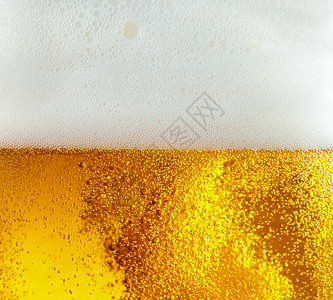 雄鹿嘶嘶作响浅啤酒背景中漂浮气泡的特写视图凉爽的夏天的质地在玻璃墙上过滤了泡沫和宏观嘶声的饮料嘶作响背景