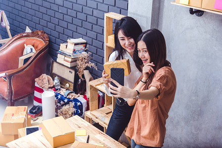 两个女人一起在网上卖东西时用手机自拍商业和人们的图片