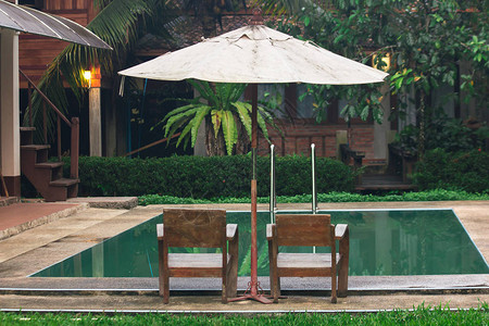 两把木椅位于游泳池旁图片