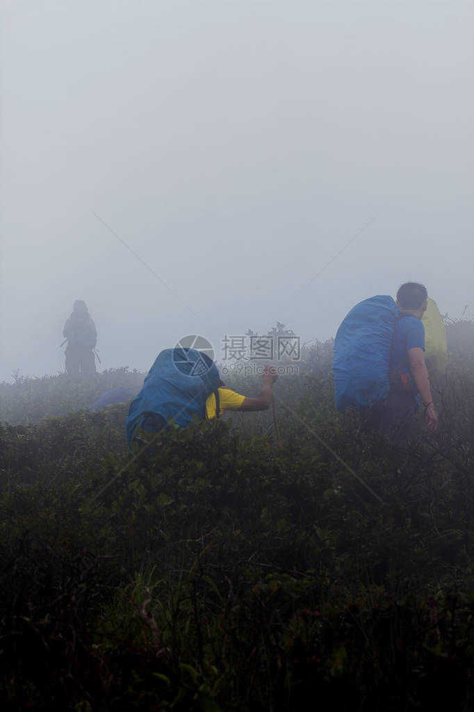 男人背着包雨中爬山图片