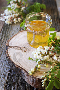 Acacia蜂蜜和木制桌上的花朵背景图片