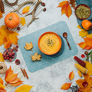 带有叶形饼干的南瓜汤和白石背景上的秋天装饰品图片