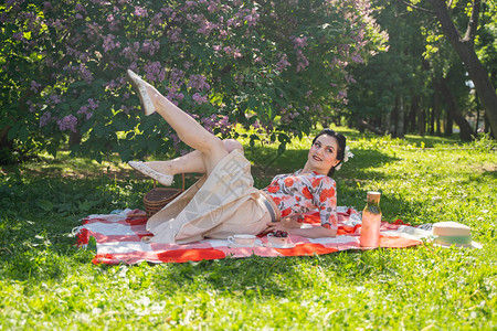 一个迷人的黑发年轻女孩独自在绿色的夏日草地上享受休息和野餐图片