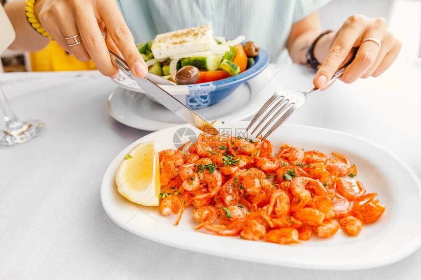 餐厅里的女孩吃着希腊西米岛的美味小虾和海产食品和美食烹图片