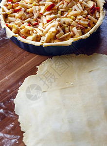 烹饪过程室内美国苹果派与深色木质背景上的酥皮糕点滚生面团从上面查看复图片