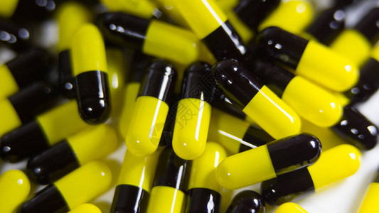 关闭许多黑色和黄色药丸和片剂药物隔离在白色背景处方药物止痛药和图片