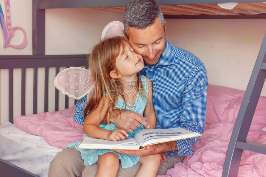 家庭两个人坐在卧室看书的床上父亲和女儿在家里共度时光父母谈话与孩子交流真实的人真图片