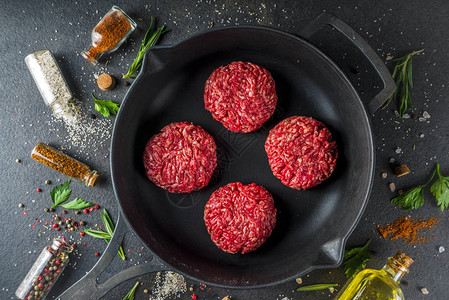 生肉碎牛肉汉堡肉饼用橄榄油烹调肉和汉堡的背景草本香料黑石或混凝土桌子图片