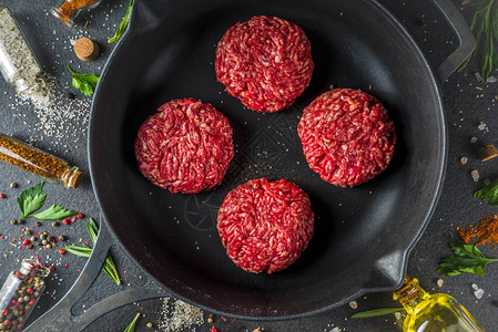 生肉碎牛肉汉堡肉饼用橄榄油烹调肉和汉堡的背景草本香料黑石或混凝土桌子图片