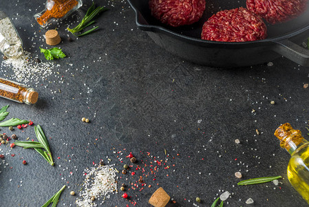 生肉碎牛肉汉堡肉饼用橄榄油烹调肉和汉堡的背景草本香料黑石或混凝土桌子图片
