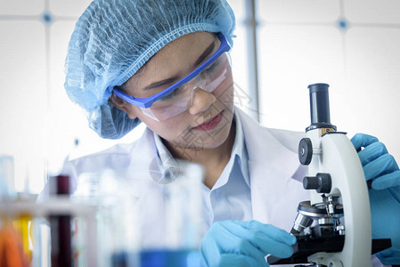 亚洲青年学生科学家在一个实验室用显微镜图片