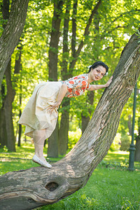漂亮可爱的年轻黑发女人独自在绿色的夏日花园里和她可爱的树合影图片