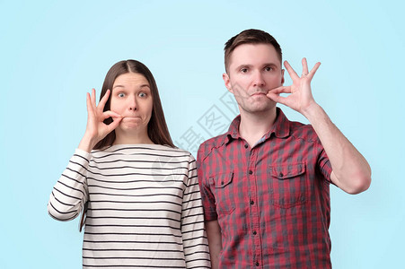 年轻哑巴夫妇拿着手指像拉链一样的嘴唇保守秘图片