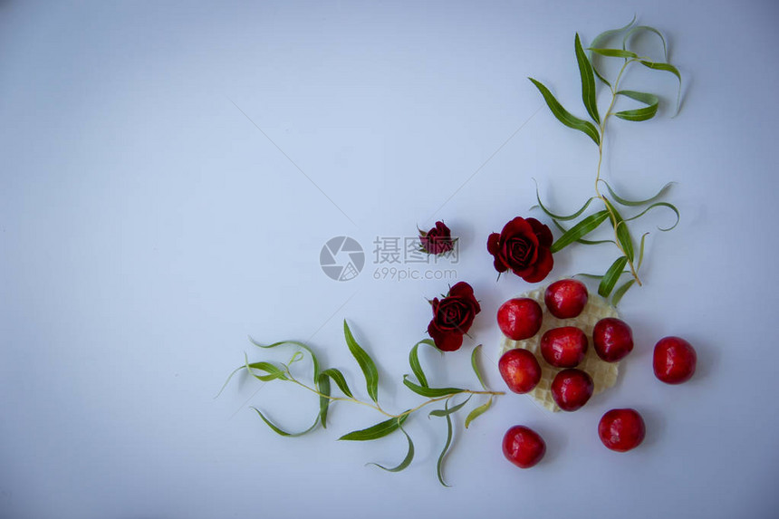 圆华夫饼上的樱桃附近的深红玫瑰白色背图片
