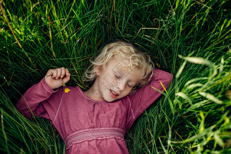 微笑着睡觉做梦的白人女孩闭着眼睛躺在草丛中图片
