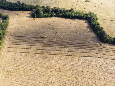 带圆形打包机的拖拉机和带耙子的拖拉机的田野鸟瞰图图片