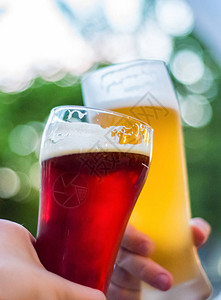两杯啤酒在手的特写视图啤酒杯在户外酒吧或图片