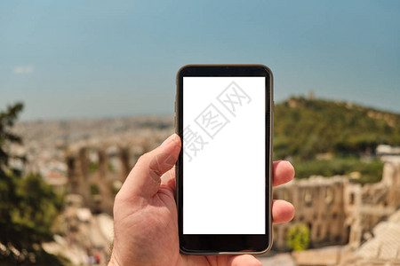 希腊雅典古区前手持智能手机的人手图片