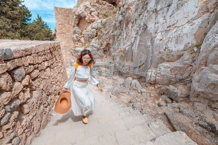 快乐的亚洲旅行者背着包走在林多斯卫城的历史和考古遗址希腊的旅游图片