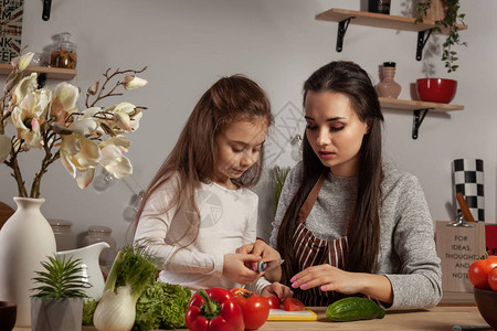 漂亮的妈和她的孩子正在做蔬菜沙拉图片