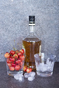 威士忌酒杯冰块和一瓶威士忌酒中的黄色甜樱桃图片
