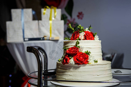 配有红玫瑰和粉红玫瑰的双层白色婚礼蛋糕图片