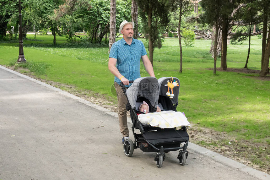 父亲和孩子在公园的双人婴儿车里图片