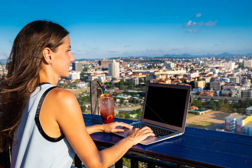 女在高楼屋顶的一家咖啡厅里用笔记本电脑工作图片