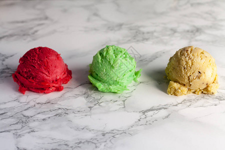 大理石桌背景上三个冰淇淋球绿色黄图片
