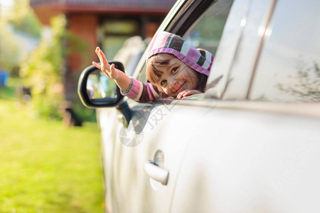车里的漂亮小女孩从车窗看挥舞着图片