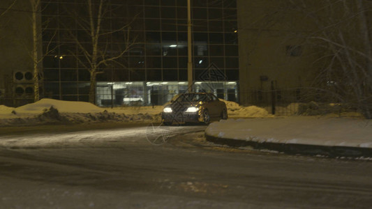 夜间在城市街道的雪路上漂流的客车图片