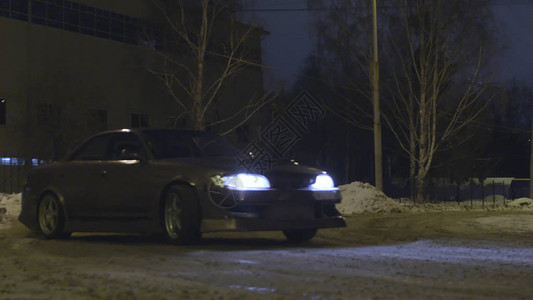 夜间在城市街道的雪路上漂流的客车图片
