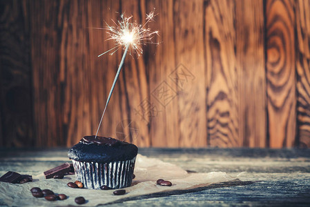 美味的巧克力蛋糕与木制背景上的烟火生日快乐的概念美味图片