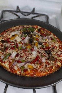自制煮熟的胡椒和洋葱比萨饼的特写图片
