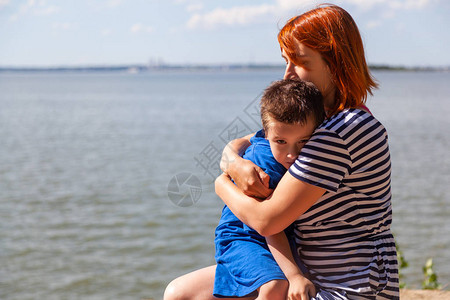 美丽的女人和她的小儿子在海面背景上颤抖图片