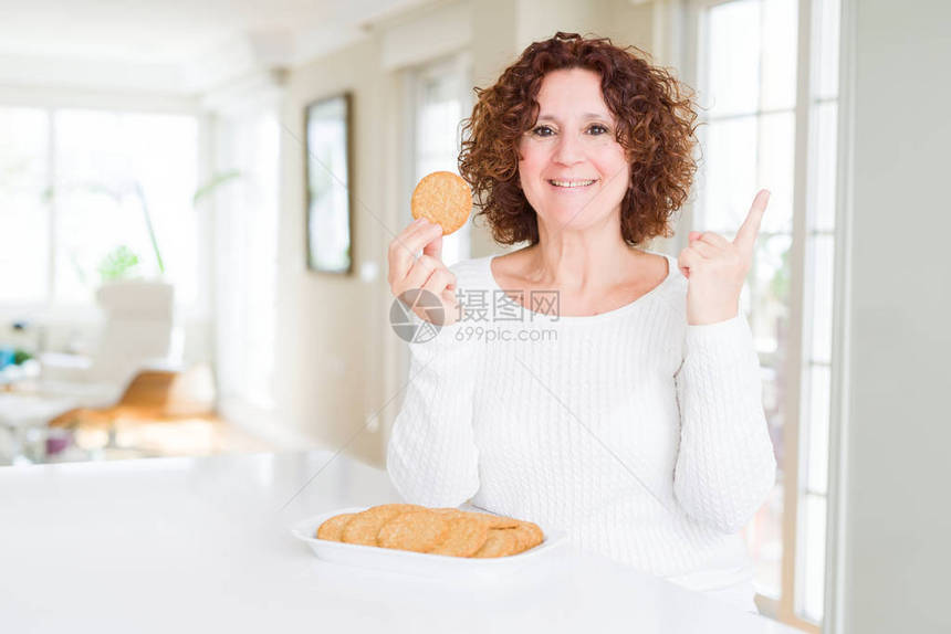 家里吃健康的老妇人在家里吃一整块玉米饼干非常开心地用手和图片