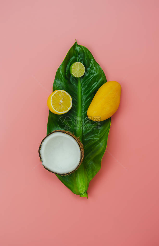 桌面视图水果热带与春夏假期和假期背景概念安排在绿叶上切片各种椰子芒果柠檬和石灰粉红色纸上的物品图片