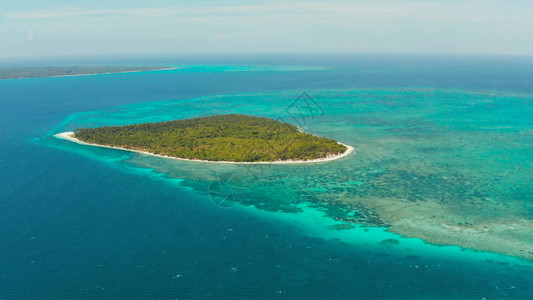 在环礁和珊瑚礁之间有白色沙滩的热带岛屿图片